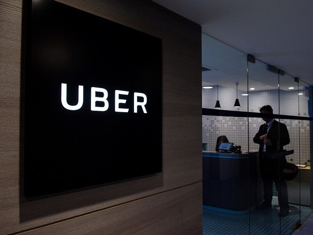 Uber signage is seen as an employee stands in the entrance of the ride-hailing giant's office in Hong Kong on March 10, 2017. Uber hit back at Hong Kong authorities on March 10 after five of its drivers were found guilty of operating without proper licences, in yet another blow …