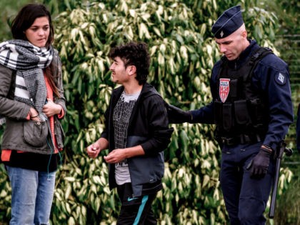 A French riot police officer arrests a migrant during a police operation to evacuate 400 I