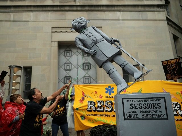Protesters pull down a mock statue of Attorney General Jeff Sessions in front of the Depar
