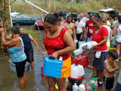 People collect water from a natural spring created by the landslides in Corozal, west of San Juan, Puerto Rico, on September 24, 2017 after Hurricane Maria struck