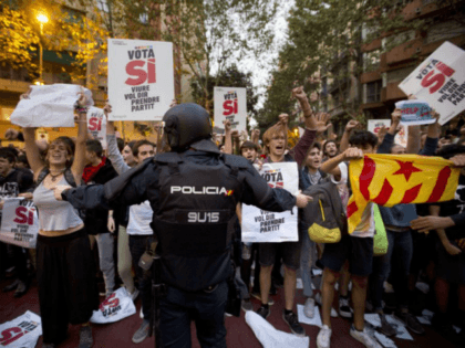 In this photo taken on Wednesday, Sept. 20, 2017, a Spanish national police officer tries to stop demonstrators protesting outside the main offices of the left wing party CUP in Barcelona, Spain. A confrontation between the central government in Madrid and independence movements in the wealthy northeastern Catalonia region has …