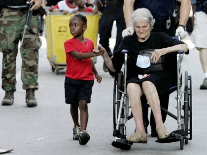 In this Sept. 3, 2005 file photo, Tanisha Belvin, 5, holds the hand of fellow Hurricane Katrina victim Nita LaGarde, 89, as they are evacuated from the Convention Center in New Orleans, La. Hundreds of people waited several days to be evacuated. (AP Photo/Eric Gay, File)