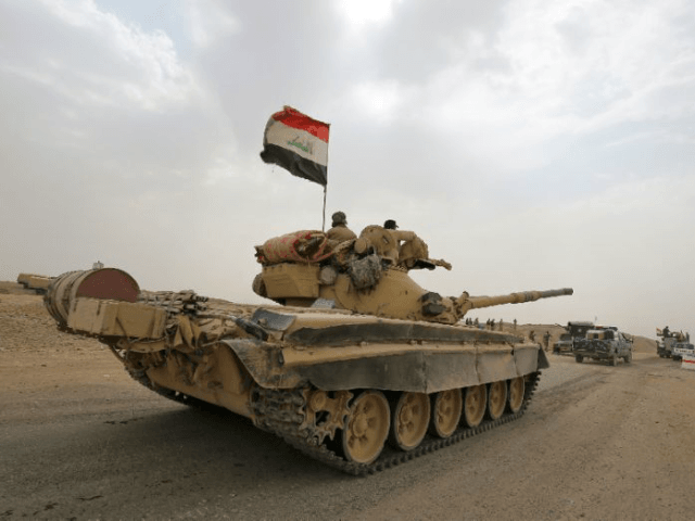 Iraqi soldiers pictured on a Russian-made T-72 tank as they advance towards the city of al