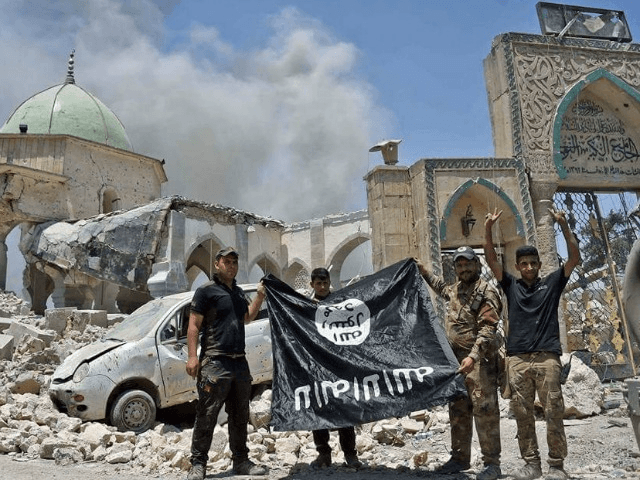 Iraqi troops hold a captured Islamic State group flag beside the ruins of the Al-Nuri Mosque on June 30, 2017 as victory over the jihadists in Mosul neared