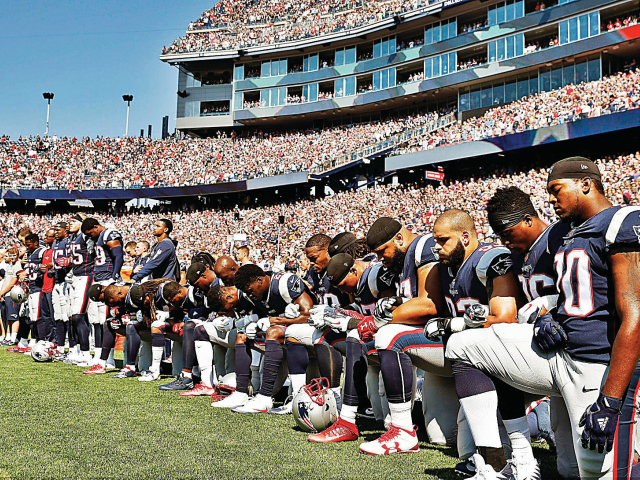 Several New England Patriots players kneel during the national anthem before an NFL footba
