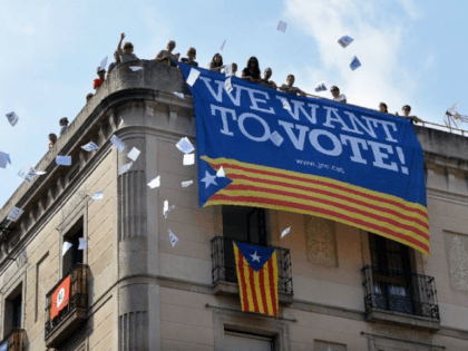 A group of people in Barcelona throw ballots for the October 1 referendum from a building with a banner in favour of the referendum, with Spain's prime minister asking Catalan leaders to admit their plans have been dealt a serious blow.