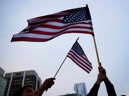 Crowd members wave American flags during a vigil downtown for the victims of a mass shooti