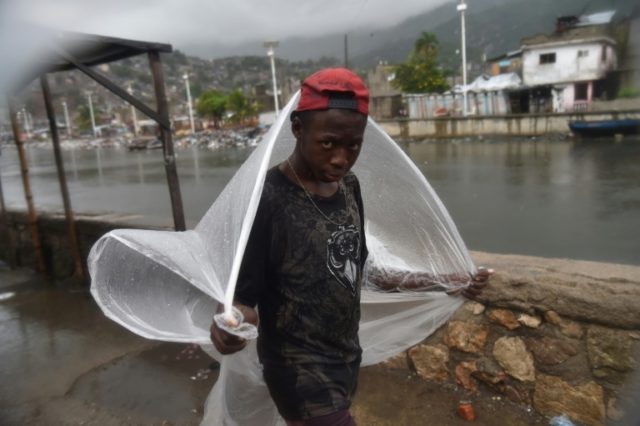 A boy takes cover from the rain in Cap-Haitien's Shada neighborhood as Hurricane Irma appr