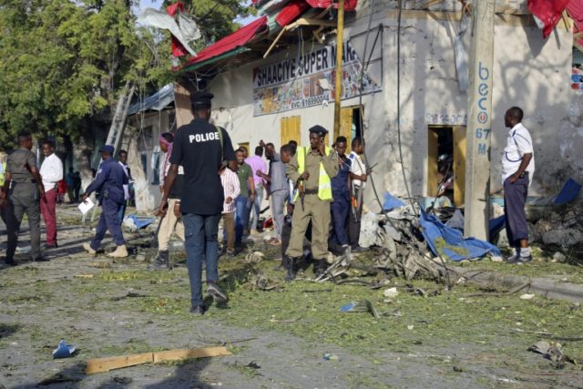 Local residents and Somali soldiers stand at site of a car bomb attack in the center of Mo