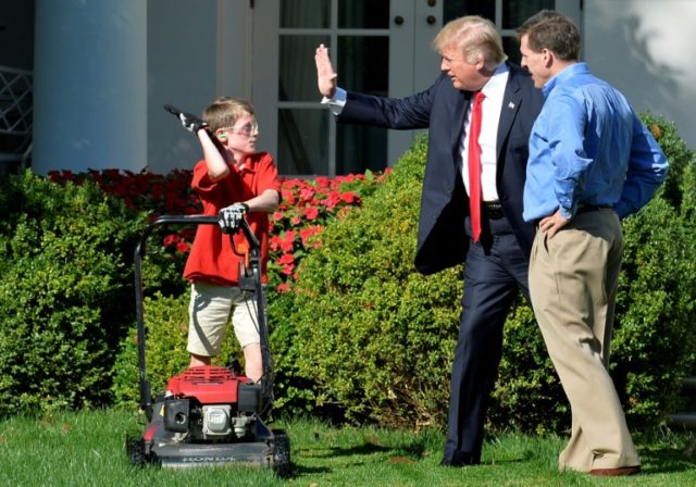 President Donald Trump high fives Frank Giaccio, 11, of Falls Church, Virginia, as he mows