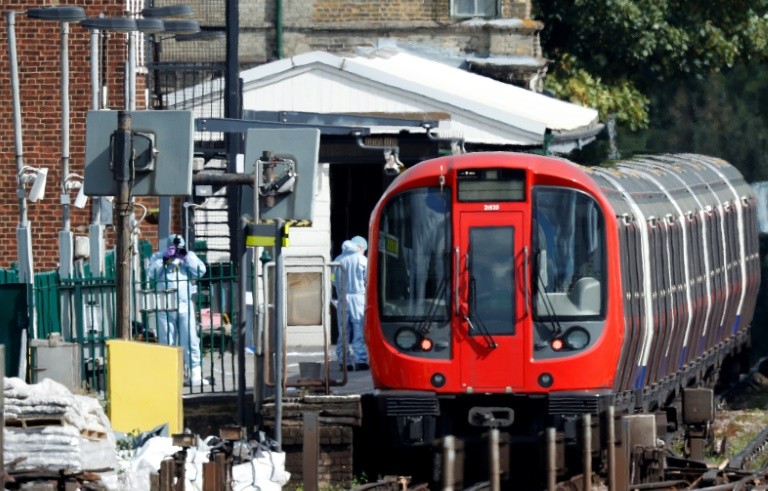 Police forensics officers work alongside an underground tube train at a platform at Parsons Green station in west London.