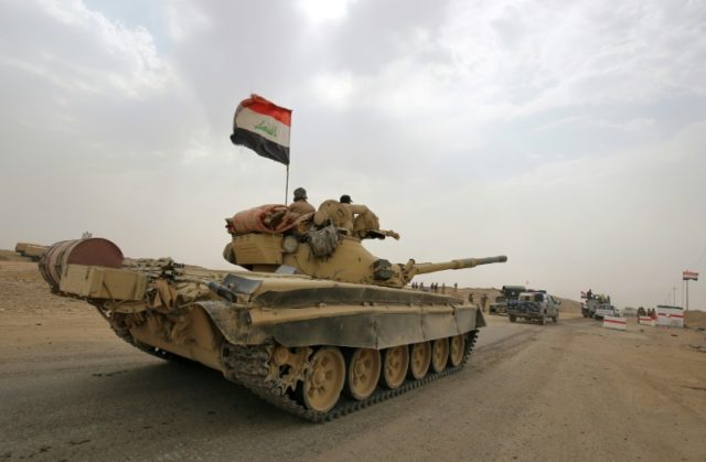 Iraqi soldiers pictured on a Russian-made T-72 tank as they advance towards the city of al