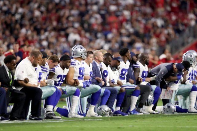 Members of the Dallas Cowboys link arms and kneel during the National Anthem before the st