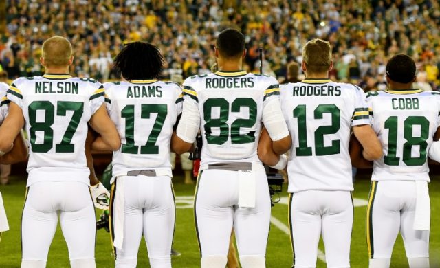 Green Bay Packers players link arms during the singing of the national anthem before the g