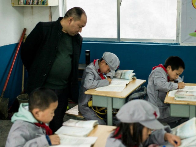 This photo taken on November 7, 2016 shows a teacher supervising students in the Yang Dezhi 'Red Army' elementary school in Wenshui, Xishui country in Guizhou province. In 2008, Yang Dezhi was designated a 'Red Army primary school' -- funded by China's 'red nobility' of revolution-era Communist commanders and their …