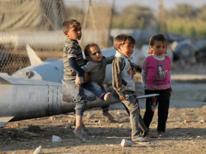 Syrian children play as they sit on the tip of an abandoned missile at the Ash'ari camp for the displaced in the rebel-held eastern Ghouta area outside the capital Damascus on October 25, 2017