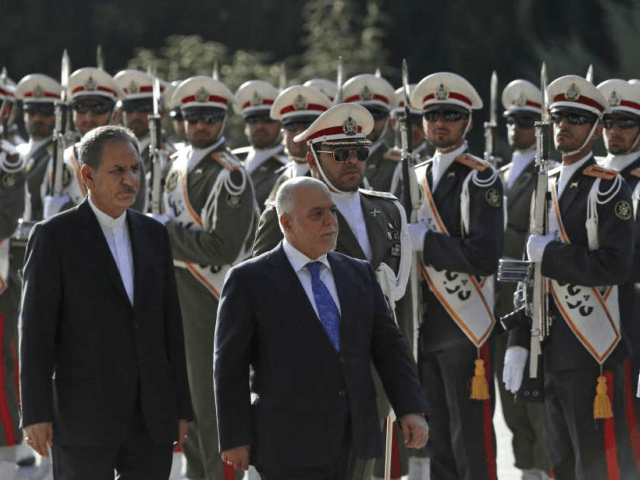 Iraqi Prime Minister Haider al-Abadi, center, reviews an honor guard as he is accompanied