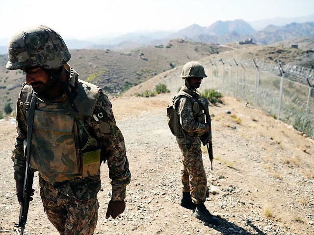 Pakistani soldiers patrol next to a newly fenced border fencing along Afghan border at Kit
