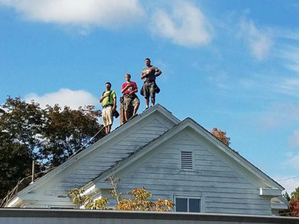 Roofers Put Hands over Hearts for National Anthem at Nearby Football Game