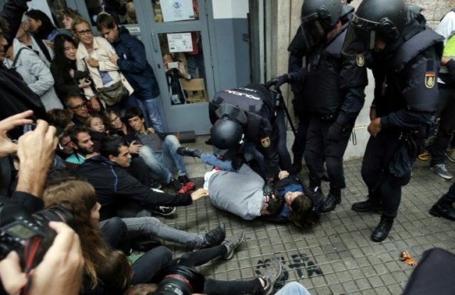 Spanish police immobilize two people outside a polling station in Barcelona as Catalonia h