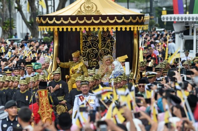 Brunei's Sultan Hassanal Bolkiah and Queen Saleha wave to crowds during Thursday's golden jubilee procession
