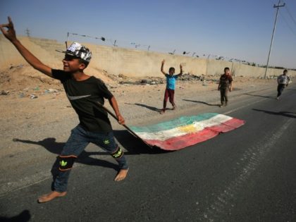 An Iraqi boy drags a Kurdish flag as Iraqi forces advance towards the centre of Kirkuk during an operation against Kurdish fighters on October 16, 2017.