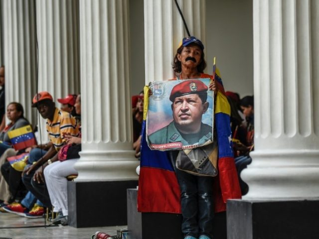 A supporter of Venezuelan President Nicolas Maduro holds a photo of his late predecessor Hugo Chavez, whose leftist ideology and government style continues to prevail in the South American country