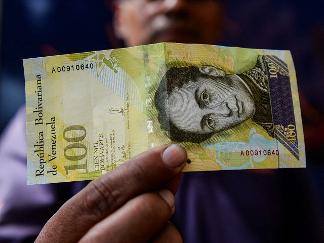 A man shows a new one hundred thousand-Bolivar-note in Caracas on November 9, 2017. The new bill is worth 29,89 US dollars in the official market and 2 dollars in the black market at November 9, 2017 exchange rate. / AFP PHOTO / FEDERICO PARRA (Photo credit should read FEDERICO …