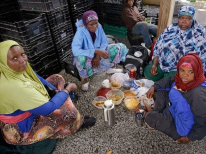 June, 2014: Somali refugees, working as farm hands, share lunch under a shelter as a steady rain falls at Red Fire Farm in Massachusetts.