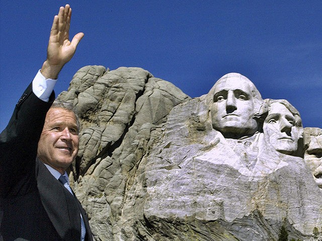 KEYSTONE, UNITED STATES: US President George W. Bush waves to the crowd at the foot of Mt. Rushmore 15 August 2002 in Keystone, South Dakota. Sculptor Gutzon Borglum started work on Mt. Rushmore 10 Aug 1927 and continued for 14 years, but only 6.5 years were actually spent sculpting due …