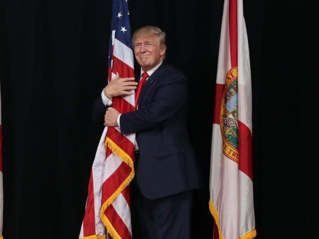 TAMPA, FL - OCTOBER 24: Republican presidential candidate Donald Trump hugs the American flag as he arrives for a campaign rally at the MidFlorida Credit Union Amphitheatre on October 24, 2016 in Tampa, Florida. There are 14 days until the the presidential election. (Photo by Joe Raedle/Getty Images)