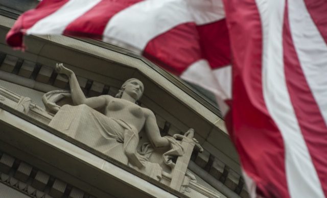 The US national flag is seen flying over a statue on the Department of Justice at the end