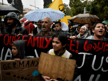 Refugees protest outside the German embassy in Athens under pouring rain, on November 8, 2