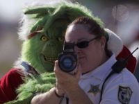 The Grinch stands behind a police officer using a laser speed detector The Grinch stands behind a police officer using a laser speed detector