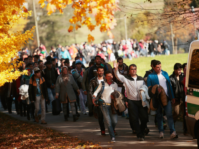 German police lead arriving migrants alongside a street to a transport facility after gath