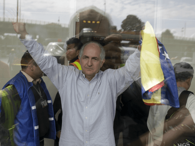 Holding a national Venezuelan flag, ousted Caracas Mayor Antonio Ledezma waves from inside