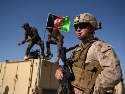 In this photograph taken on August 28, 2017, a US Marine looks on as Afghan National Army soldiers raise the Afghan National flag on an armed vehicle during a training exercise to deal with IEDs (improvised explosive devices) at the Shorab Military Camp in Lashkar Gah in Helmand province. Marines …