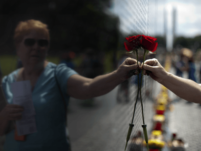 Carol Bates, of California, holds a rose against the Vietnam Veterans Memorial in Washington, Sunday, June 18, 2017, during the Vietnam Veterans Memorial Fund's annual Father's Day Rose Remembrance in honor of Father's Day. (AP Photo/Carolyn Kaster)