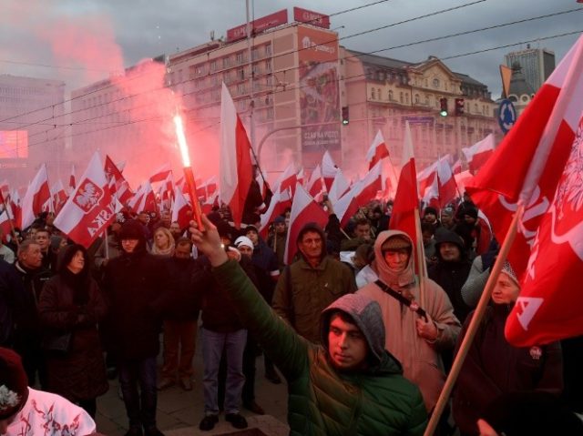 Demonstrators burn flares and wave Polish flags during the annual march to commemorate Pol