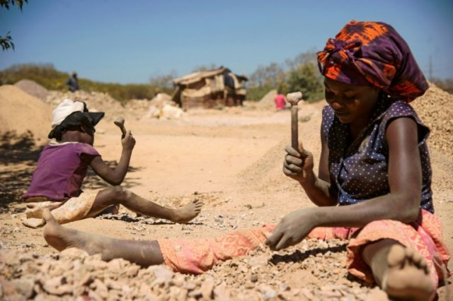 A child and a woman break rocks extracted from a cobalt mine at a copper quarry and cobalt