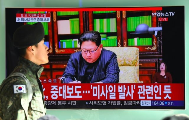A South Korean soldier walks past a television screen showing North Korean leader Kim Jong