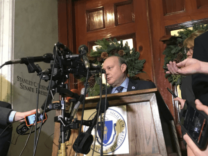 Massachusetts Senate President Stan Rosenberg speaks from behind a podium outside his offi