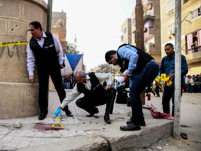 Egyptian security members and forensic police inspect the site of a gun attack outside a church south of the capital Cairo, on December 29, 2017. A gunman opened fire on a church, killing at least nine people before policemen shot him dead, state media and officials said. / AFP PHOTO …
