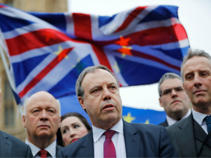 Democratic Unionist Party (DUP) Deputy Leader Nigel Dodds (C) speaks to journalists outside the Houses of Parliament in central London on December 5, 2017, as demonstrators wave Union and European Union (EU) flags behind. British Prime Minister Theresa May scrambled Tuesday to salvage a deal over the post-Brexit border in …