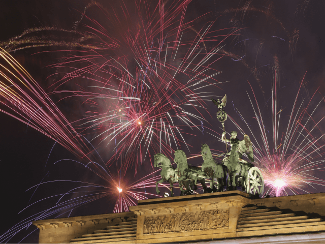 BERLIN, GERMANY - JANUARY 01: Fireworks explode behind the Brandenburg Gate at midnight on