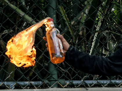 A student at the Central University of Venezuela throws a Molotov cocltail during clashes
