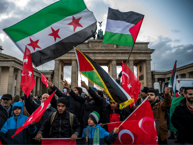 Demonstrators wave Palestinian, Turkish and Syrian flags in front of the Brandenburg Gate,