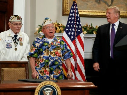 Alexander Horanzy, left, and President Donald Trump listen to Mickey Ganitch sing a song about Pearl Harbor during an event with survivors of the attack, in the Roosevelt Room of the White House, Thursday, Dec. 7, 2017, in Washington. (AP Photo/Evan Vucci)