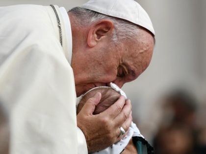 TOPSHOT - Pope Francis kisses a baby as he arrives for his weekly general audience at the