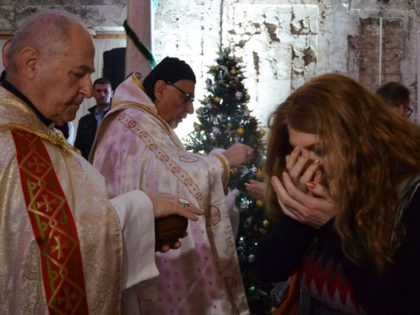 An Iraqi receives the Eucharist during a Christmas mass at the Saint Paul's church on December 24, 2017 in the country's second city Mosul. Hymns filled a church as worshippers celebrated Christmas for the first time in four years after the end of jihadist rule. Tens of thousands of Christians …